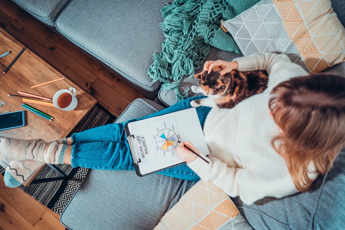 Top View Relaxed Young Woman Drawing Work-Life Balance Wheel Sitting on the Sofa with Cat Pet at Home. Self-Reflection and Life Planning. Coaching Tools. Finding Balance in Your Life. Selective Focus.